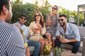 Happy friends talking and drinking cocktails at terrace party outdoor - Young millennials people having fun at weekend summer - Youth lifestyle and nightlife concept