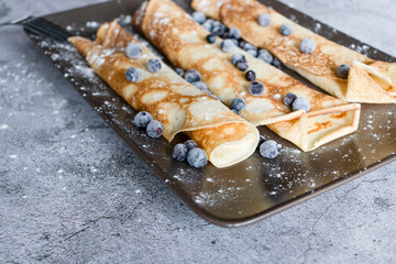 Homemade pancakes with blueberries. On gray plates and concrete background