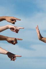 Hands pointing to a person making the stop gesture with the palm. Accusation and guilt concept.
