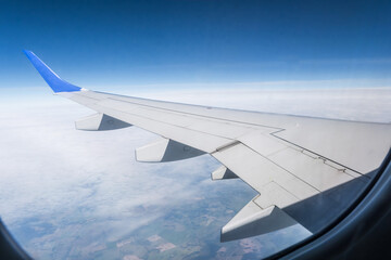 Obraz premium aircraft wing from the aircraft window overlooking the blue sky and beautiful clouds