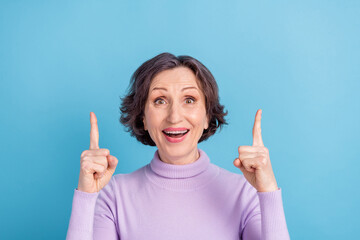 Photo of aged woman happy positive smile point fingers empty space advert choice decison isolated over blue color background