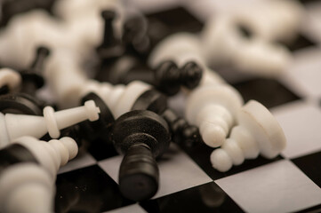 A chess board and black and white chess pieces on a wooden table, close-up, selective focus.