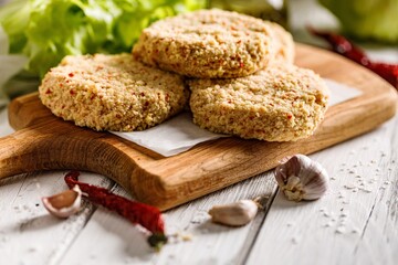 Close-up raw chicken hamburger cutlet breaded with paprika and garlic. Homemade minced poultry cutlet with spices. White rustic background. Copy space