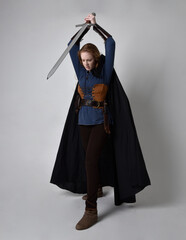 Full length, portrait of red haired woman wearing medieval viking inspired costume and flowing...