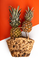 Beautiful pineapples with basket on orange background