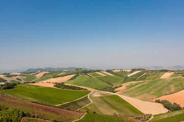 Aerial view of typical Italian landscape with cultivated fields and blue sky.
