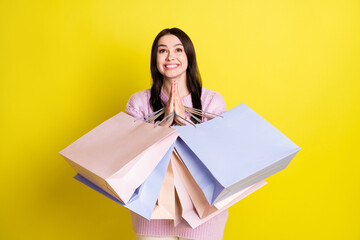Photo of pleading millennial lady hold bags thanks wear sweater isolated on yellow color background