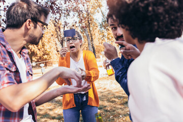 Naklejka premium Group of young people hangout in the park.They are play guess who game.