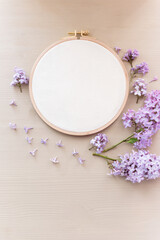 Flat lay top view photo of a mockup with embroidery hoop and llilac flowers.