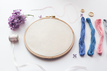 Flat lay top view photo of a mockup with embroidery hoop and llilac flowers. - obrazy, fototapety, plakaty