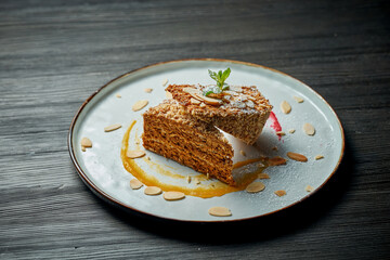 Portion of sweet waffle cake with condensed milk in a white plate on a wooden background