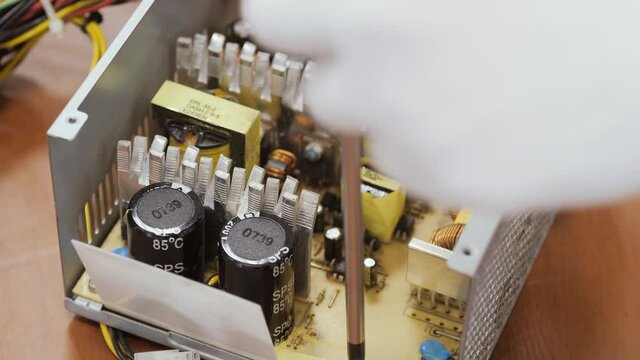 Close up of a service worker disassembles a PC power supply for cleaning.
