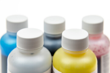 Five plastic bottles with different inks for ink-jet printer on a light background