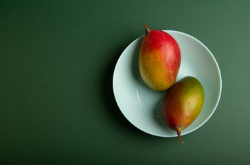Two mango on green table with plate