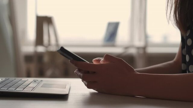 Phone communication. Online chat. Gadget technology. 5G internet. Woman hands using smartphone typing text sms message on social media at desk with laptop at home.