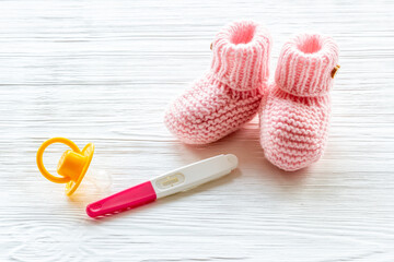 Pregnancy test and pink baby girl booties. Morherhood and pregnancy concept
