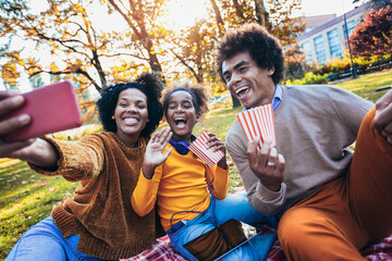 Mixed family having fun while picnicking in the park make selfie photo.