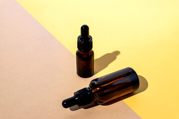 Glass dropper bottles with a pippette on double beige and yellow background. Nature Skin concept. Organic Spa Cosmetics. Trendy concept.