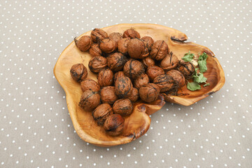 Fresh harvest walnuts with shells and water drops in wooden bowl. Walnuts details