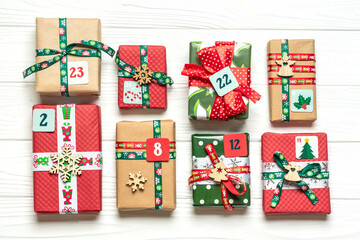 Handmade wrapped red, green gift boxes decorated with ribbons, snowflakes and numbers, Christmas decorations and decor on white table Xmas advent calendar concept Top view Flat lay Holiday card