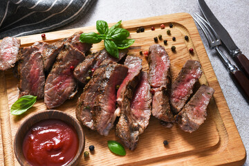 Rare beef steak, slice on wood board. View from above.