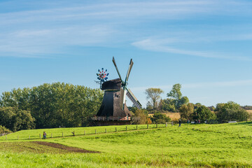 Fototapeta premium Eine grüne Wiese mit einer Windmühle im Hintergrund