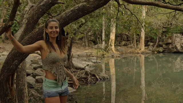 Woman Holding On Tree While Walking At Rocky Waterhole - Cedar Creek Falls, QLD Australia. Medium Shot