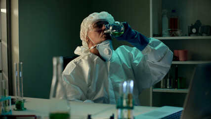 Crazy aged scientist drink from test tube in chemical laboratory