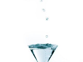 Close-up of water drop falling into a glass on white background