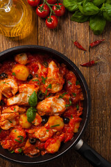 Traditionally prepared cod in Spanish. Served in tomato sauce with boiled potatoes, olivki and basil. Top view.