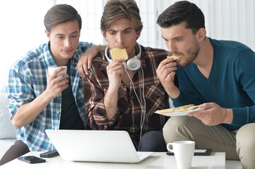 group of friends sitting on sofa with laptop