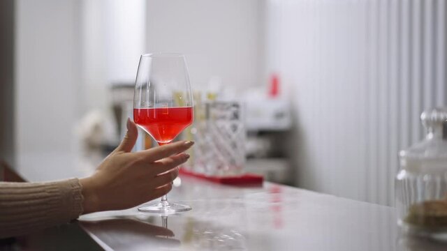 Female Caucasian bartender passing glass of aperol to client over counter in slow motion. Young woman serving customer in pub bar cafe indoors. Restaurant business concept