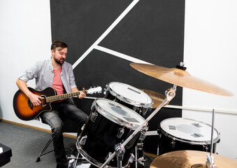 Fototapeta premium Male musician is playing music on wooden acoustic guitar, capture chords by finger.