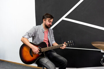 Male musician is playing music on wooden acoustic guitar, capture chords by finger.
