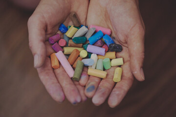 Colored crayons, pastels in the hands of the girl.
