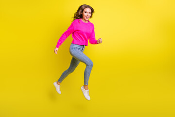 Full length photo of adorable purposeful wavy young woman wear pink sweater jumping running isolated yellow color background