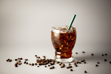 Iced americano coffee with coffee beans on grey background, Glass of black coffee, Beverage at coffee shop.