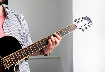 Male musician is playing music on wooden acoustic guitar, capture chords by finger.