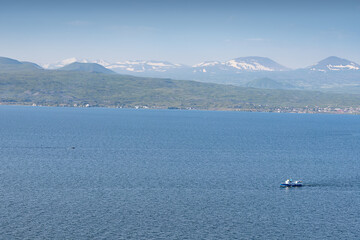 Obraz premium Ferry boat or fishing ship transporting passengers on Lake Sevan in Armenia. Water cruise and tours concept
