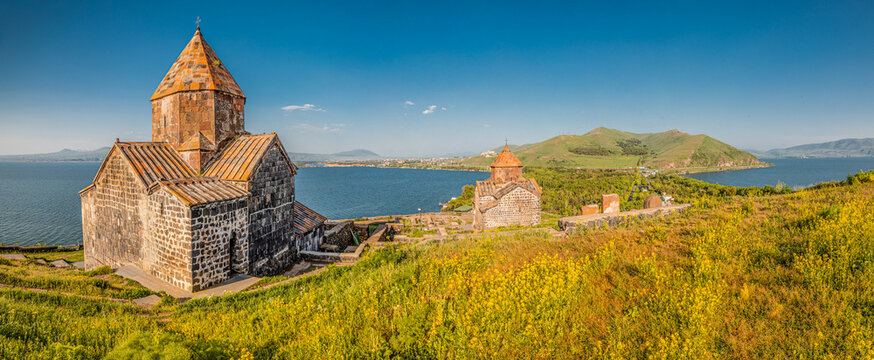 Morning calm panoramic view from the peninsula viewpoint to Sevanavank Monastery overlooking Lake Sevan in sunny weather