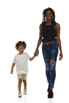 African mother and her son are walking together towards camera. Front view, isolated.