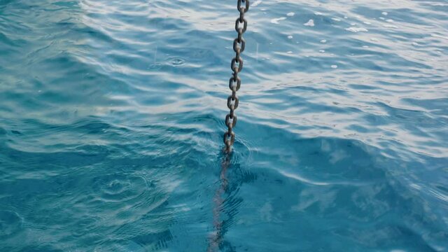Lifting the anchor chain from the bow of a sailing catamaran from the great depth of the blue sea