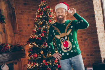 Portrait of attractive cheerful guy wearing santa cap ball festal day december celebratory at modern loft industrial style indoors