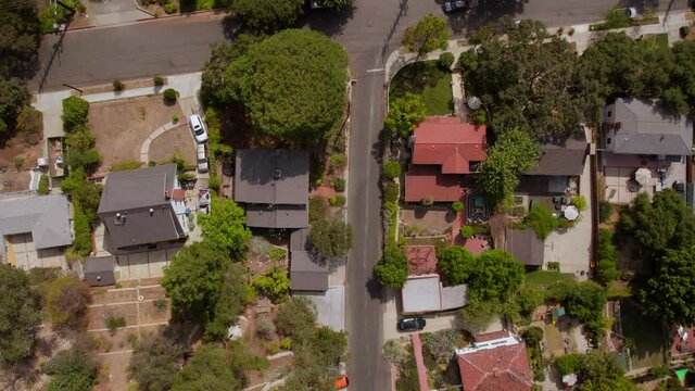 Overhead aerial view of houses and street in Eagle Rock neighborhood in Los Angeles, California with scrolling up to reveal a car pulling into a parking spot in a parking lot.