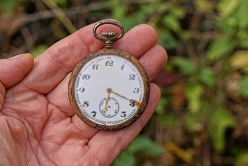 one big round old retro pocket watch lie on the fingers on the hand in the street