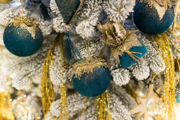 Close up of holidays location with toys and garlands on blue white and gold Christmas tree