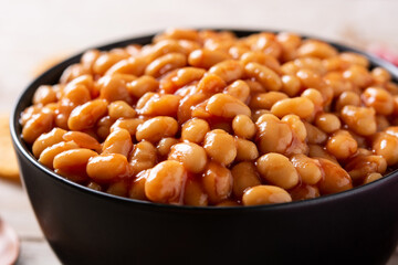 White beans in tomato sauce in bowl on wooden table	