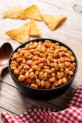 White beans in tomato sauce in bowl on wooden table	
