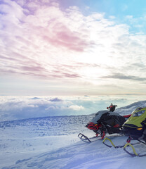 two professional sports snowmobiles on the top of the mountain in the morning without a rider. the concept of advertising recreation and travel on snow bikes. high quality photos - obrazy, fototapety, plakaty
