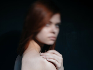 pretty red-haired woman naked shoulders posing close-up dark background